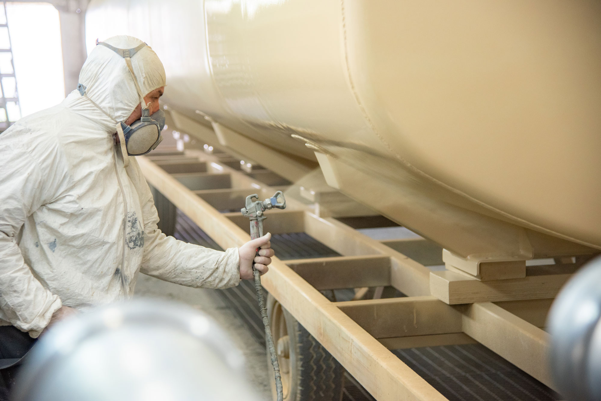 Worker painting a car bumper.